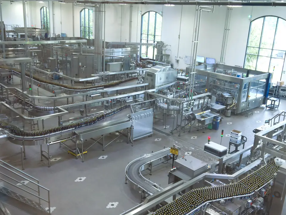 A bright modern bottling plant hall with stainless steel conveyors and filling machines