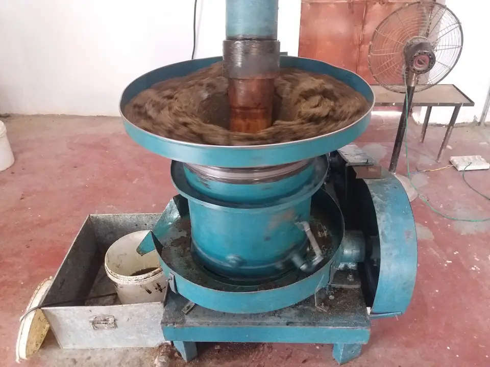 A seed press machine used for making mustard oil, with crushed seeds in the hopper